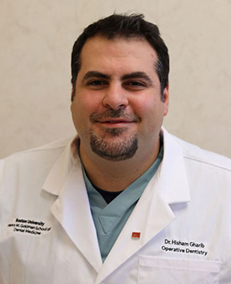 The image shows a man wearing a white lab coat, smiling and posing for the photo.