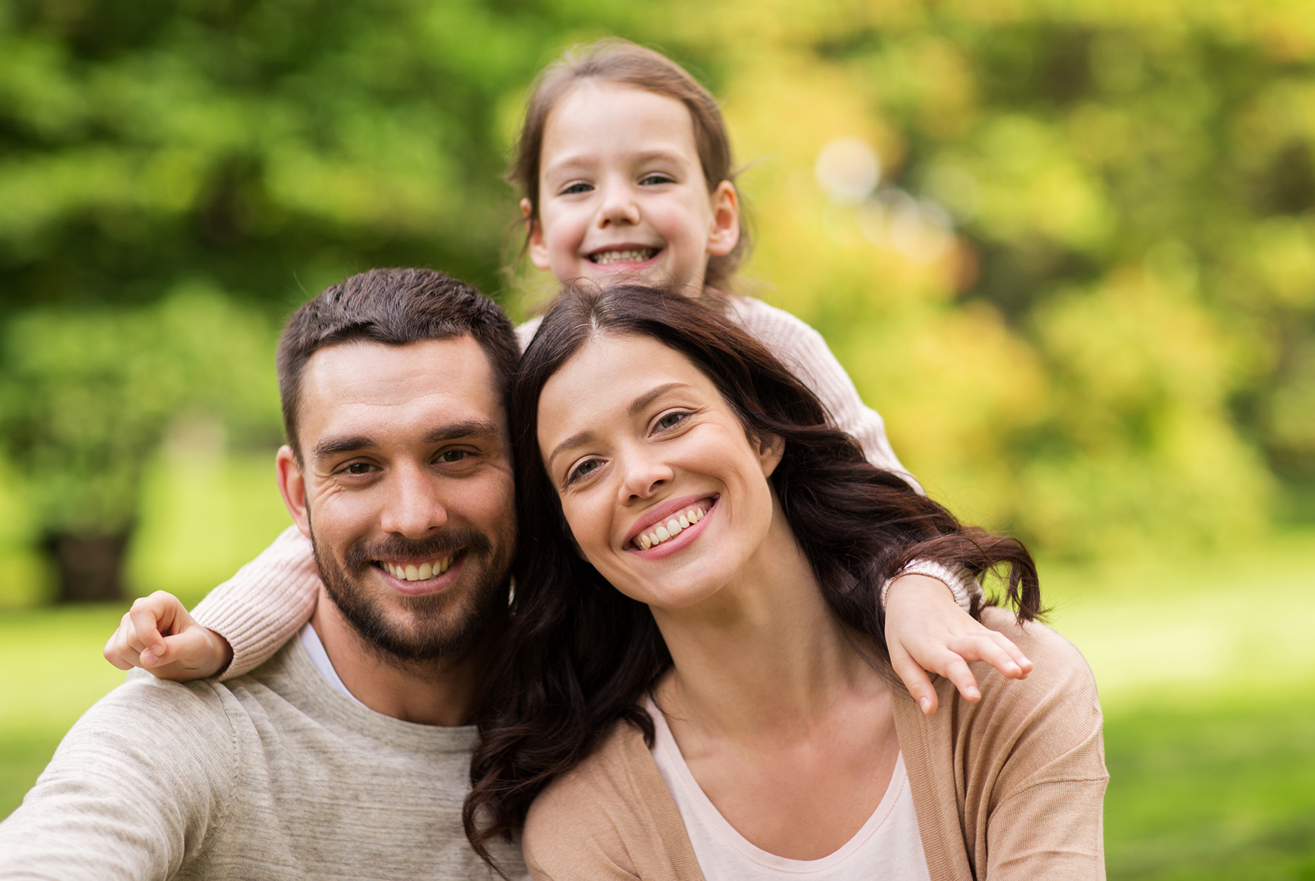 The image shows a family of four, with a man, woman, and two children posing for a photo in an outdoor setting.