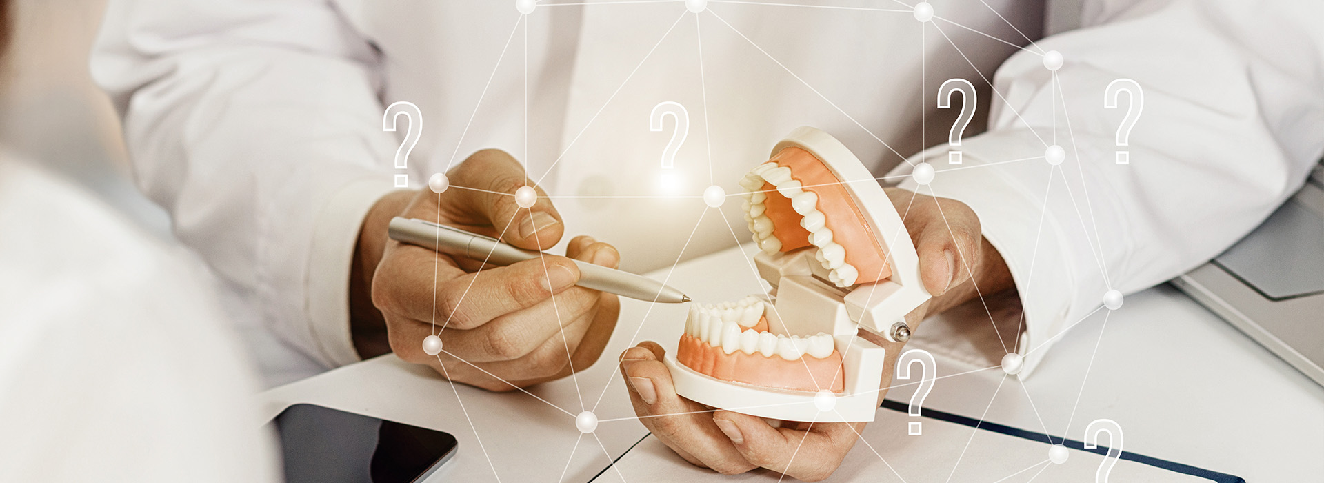 A dental professional examining a set of teeth on a digital tablet, with a close-up view of the dentition.