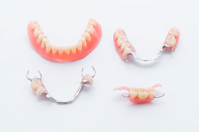 The image shows a collection of dental appliances, including a set of teeth with braces and a pair of dentures, displayed against a white background.