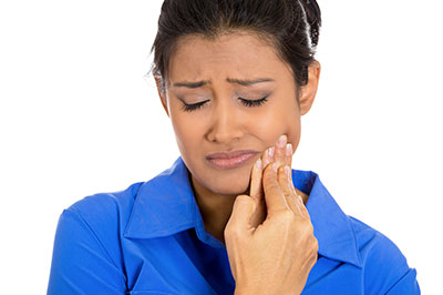 The image shows a woman with her eyes closed, holding her face and looking distressed.