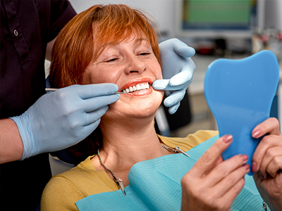 A woman in a dental chair being fitted with a new set of teeth, surrounded by dental professionals.