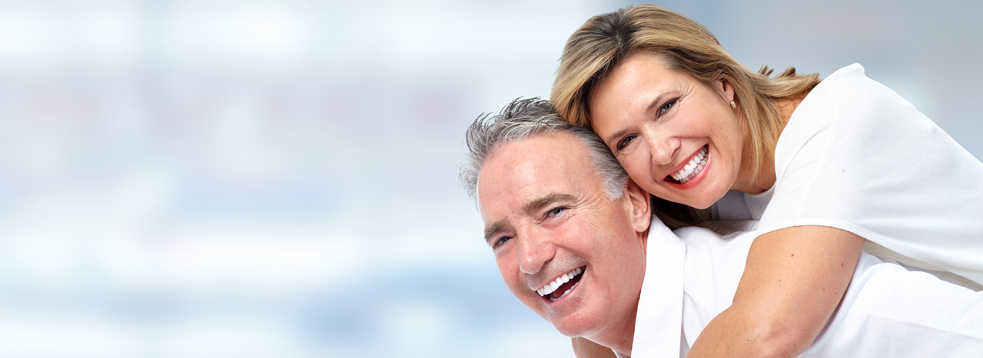 A couple smiling at the camera, with a blurred background.