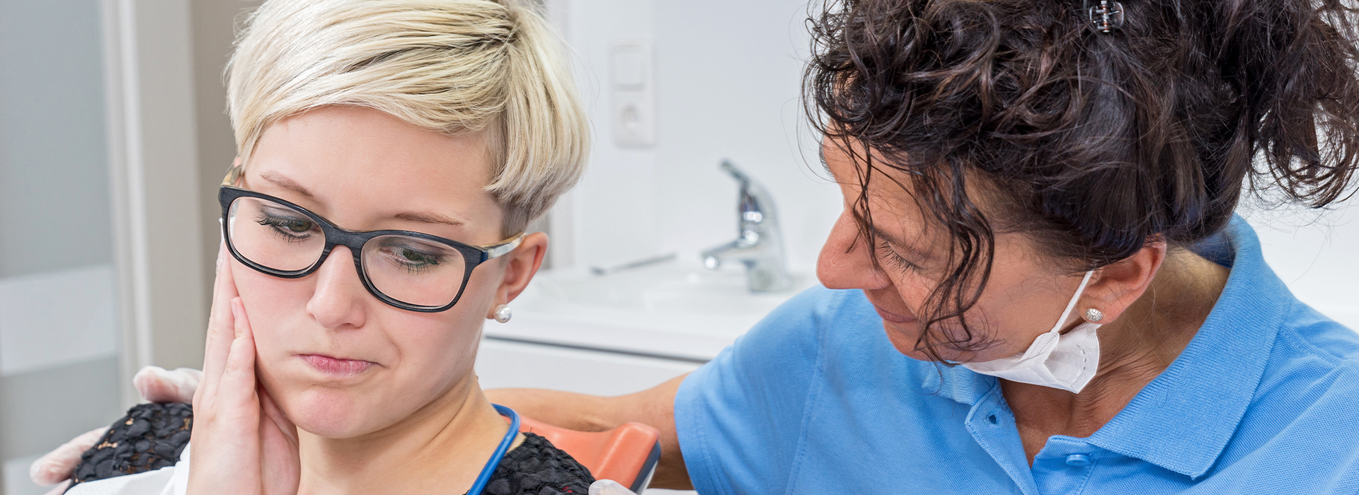 The image depicts a dental hygienist performing a dental cleaning on a patient, with both individuals wearing protective eyewear.