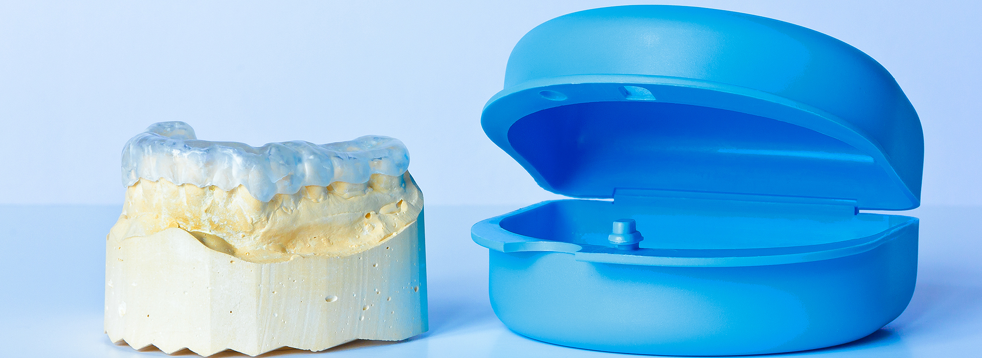 An image showcasing a blue plastic dental implant and a yellow plastic dental crown placed next to each other.