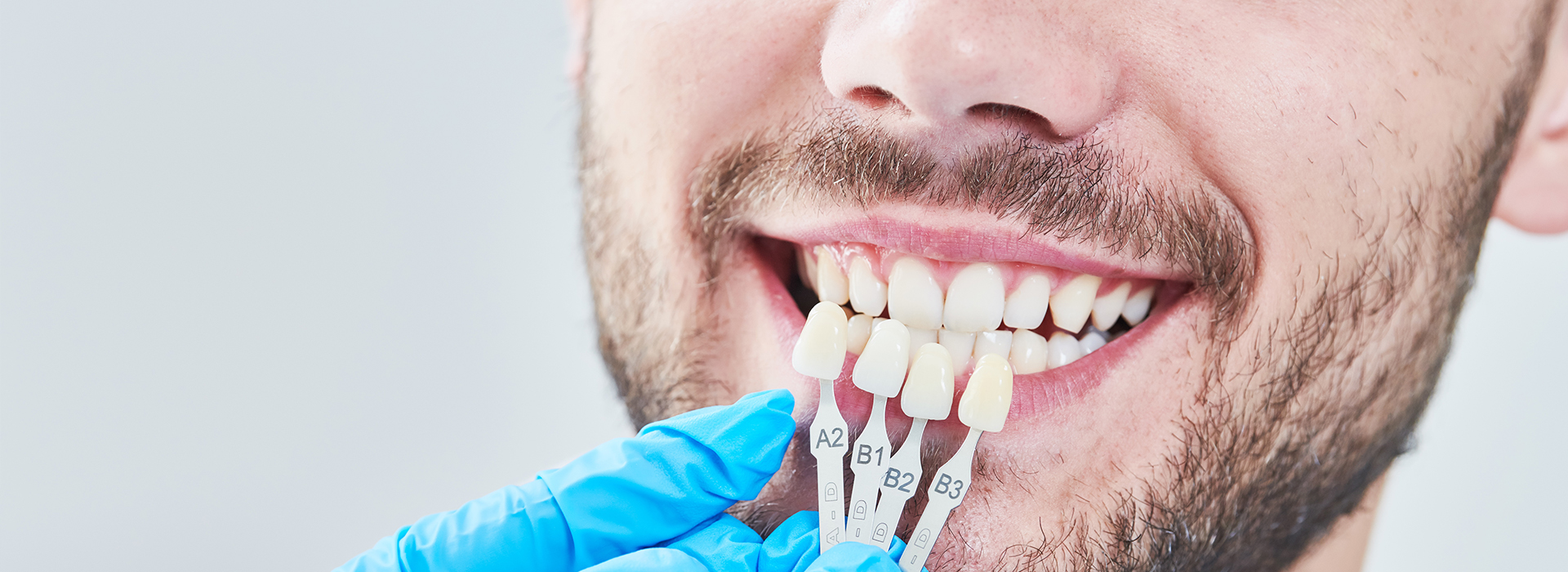 A man in a blue surgical mask holding dental implants with a smile.