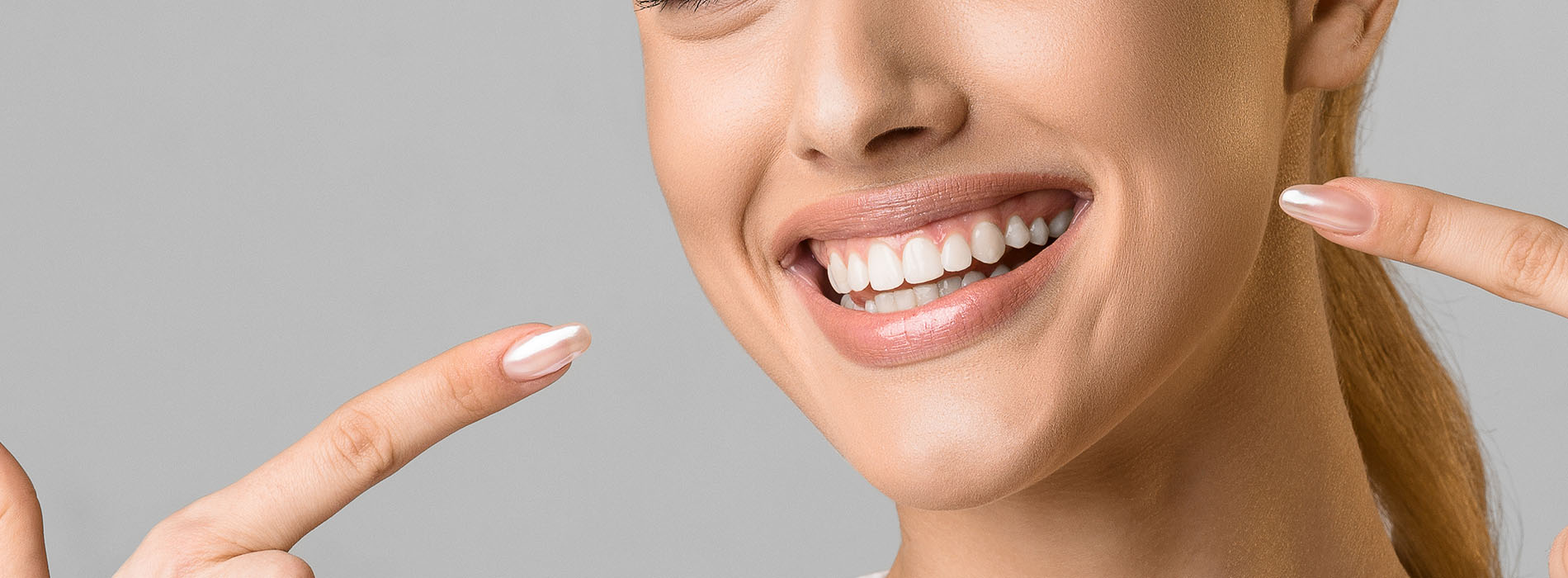 A smiling woman with a manicure, holding up her index finger.