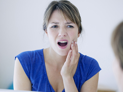 Woman with hand on mouth, showing concern or surprise.