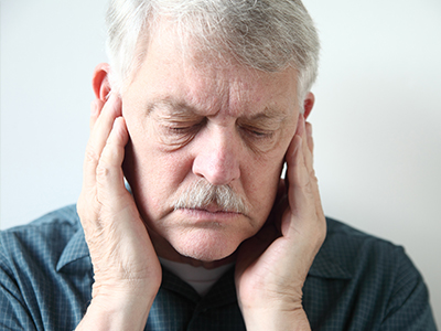 The image shows a man with his eyes closed, holding his face in his hands, appearing to be asleep or resting.